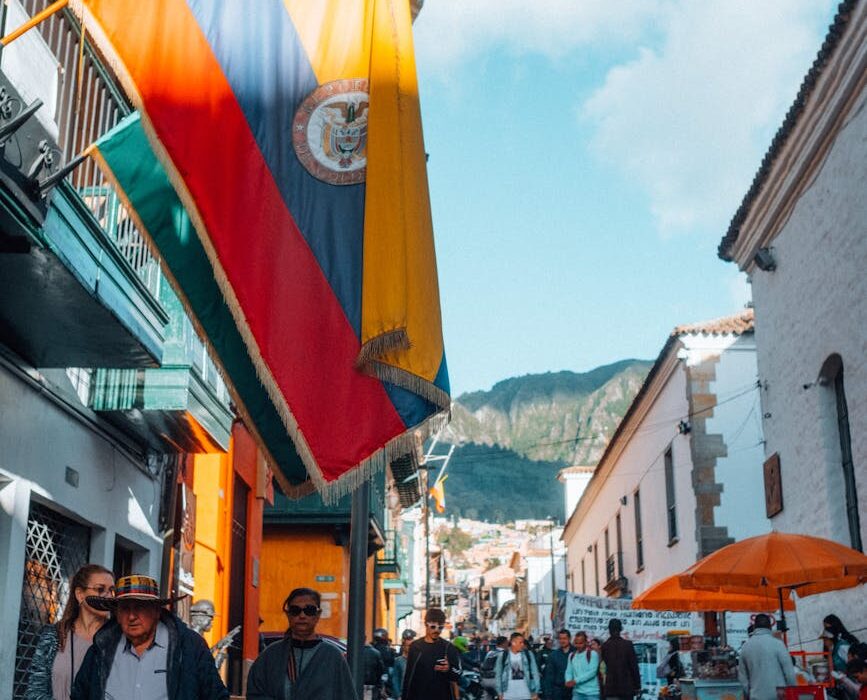 Vibrant Bogotá street scene featuring Colombian flag and bustling daytime crowd.